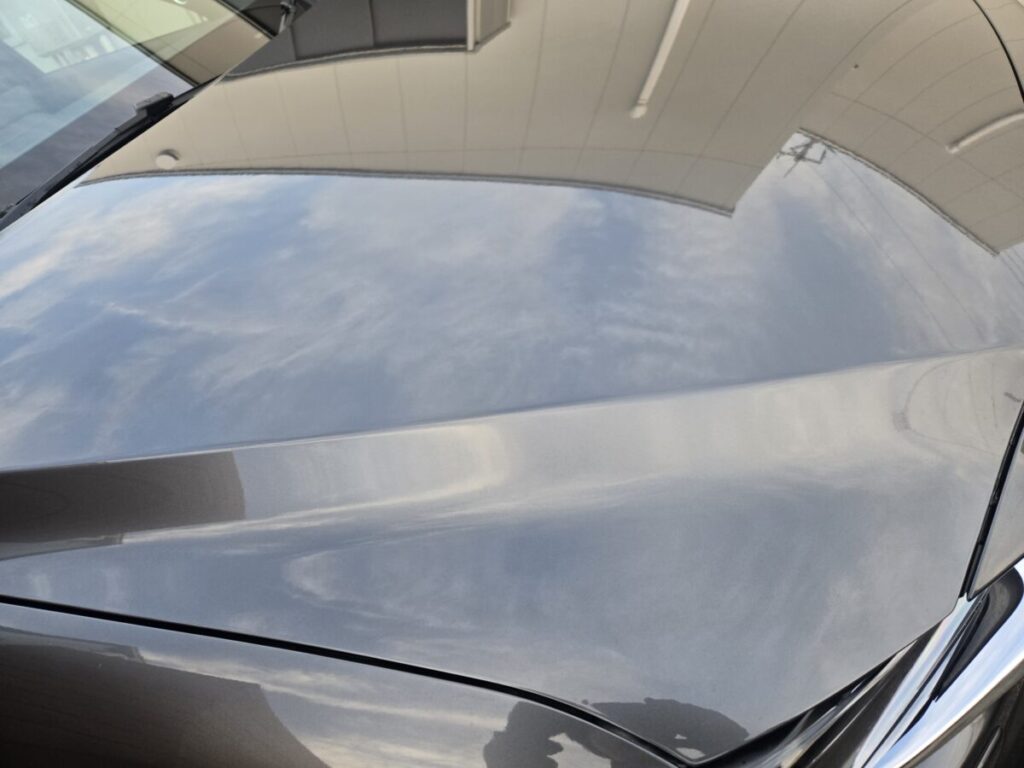洗車とコーティング施工後にツヤが戻り空や建物が映り込む車のボンネット