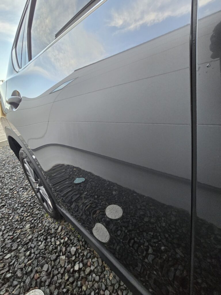 洗車とコーティング後に艶が出て周囲が映り込む車のサイドパネル