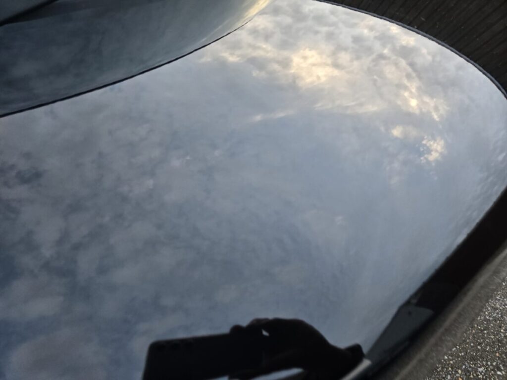 洗車後に空と雲を映す黒いホンダN-BOXのボンネット